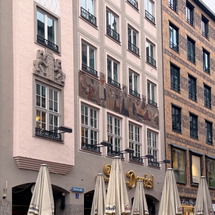 Die Szene des Sgraffito in der Weinstraße 1 wirkt wie ein Band an der Hausfassade.