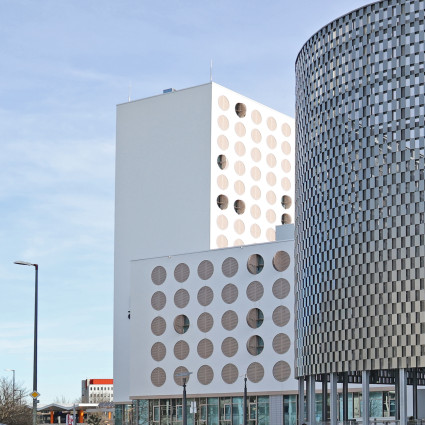Das Hotel Revo mit seinen Bullaugen-Fenstern an der Carl-Wery-Straße mit angrenzender Park+Ride-Anlage