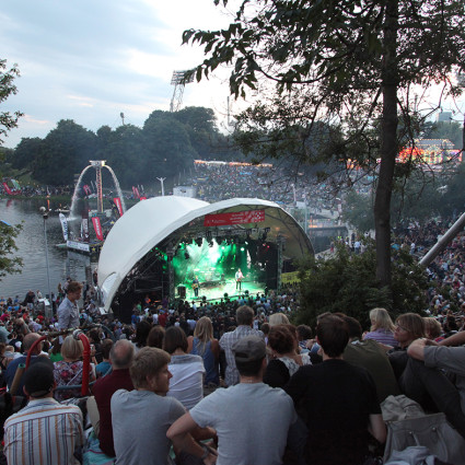 Das Theatron ist in die Kulisse des Parks und Sees im Hintergrund eingebettet.