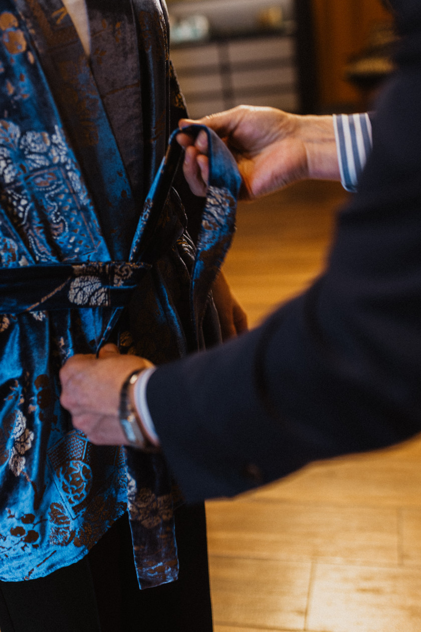 Auf diesem Foto hat eine Kundin einen blauen Kimono an, der gerade von einem Verkäufer zugebunden wird. Man sieht keine Gesichter und nur einen kleinen Ausschnitt des Kimonos.