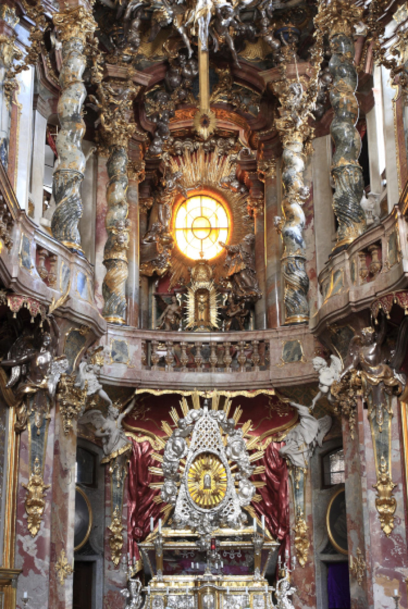 Auf diesem Foto ist in Nahaufnahme der Altar der Kirche zu sehen. Dieser ist stark verziert mit Stuck und Dekorationselementen.