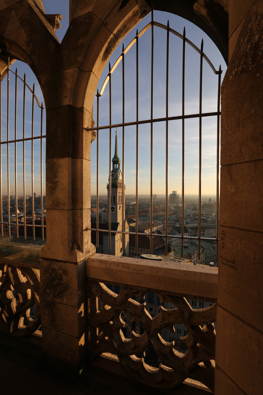 Auf diesem Foto sieht man einen Blick von einem Balkon durch Gitterstäbe auf einen Turm und runter auf die Stadt.