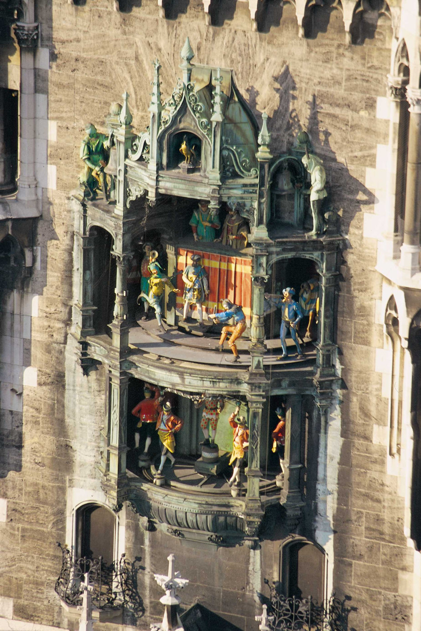 Auf diesem Foto sieht man in Nahaufnahme das Glockenspiel am Neuen Rathaus. Das Glockenspiel befindet sich auf zwei Ebenen. Im Glockenspiel sind bunte Figuren zu sehen. Das Glockenspiel befindet sich an einer Wand.